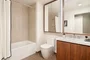 Luxurious bathrooms feature a walnut vanity, white quartz counters, and a mirrored medicine cabinet with integrated lighting