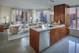 Aspire to culinary greatness in The Emerson's open kitchen with breakfast bar, featuring professional stainless steel appliances from Fisher & Paykel and Bosch, set against walnut cabinetry with Caesarstone counters and a full-height, tiled backsplash.