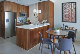 Aspire to culinary greatness in The Emerson's open kitchen with breakfast bar, featuring professional stainless steel appliances from Fisher & Paykel and Bosch, set against walnut cabinetry with Caesarstone counters and a full-height, tiled backsplash.