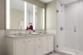 Luxuriate in master baths featuring white natural stone vanity, Kohler fixtures and accessories in polished chrome, and natural stone tile floor in white herringbone tile.