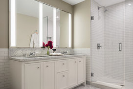 Luxuriate in master baths featuring white natural stone vanity, Kohler fixtures and accessories in polished chrome, and natural stone tile floor in white herringbone tile.