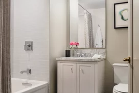 Luxuriate in master baths featuring white natural stone vanity, Kohler fixtures and accessories in polished chrome, and natural stone tile floor in white herringbone tile.