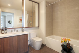 Luxurious bathrooms feature a walnut vanity, white quartz counters, and a mirrored medicine cabinet with integrated lighting