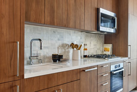 White quartz kitchen counter with a full-height Carrara marble tile backsplash