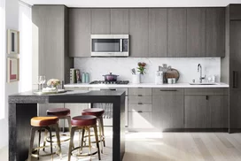 Open kitchens with custom grey-oak cabinetry, Bosch appliances, white Caesarstone counters and a Calacatta Caldia marble slab backsplash.